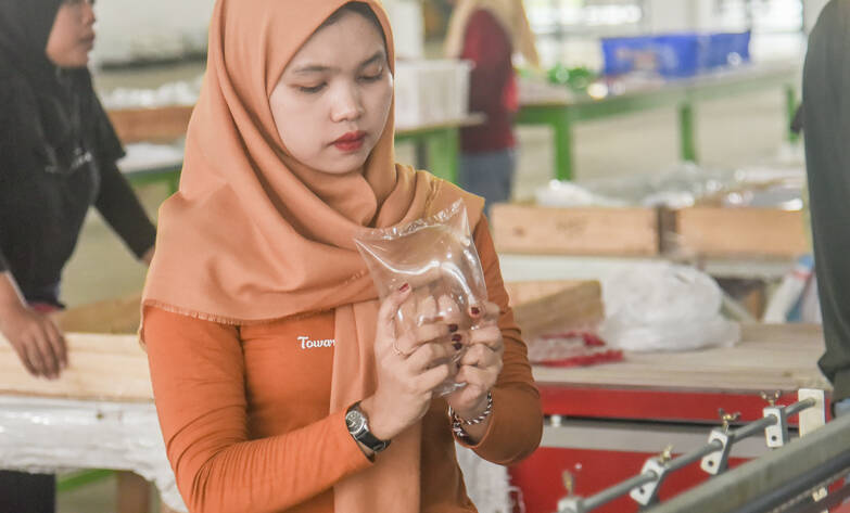 Image of PT Sinergi Handal Interpack Supervisor checking the plastic product for quality control