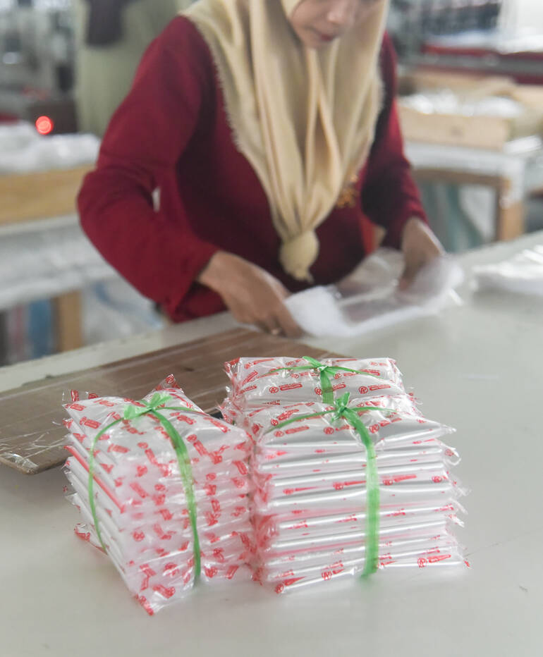 Paked polypropylene PP plastic bags while a person in the background packs